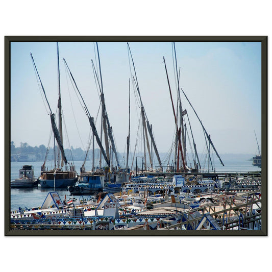 Photographie montrant un rassemblement de félouques traditionnelles égyptiennes avec leurs hauts mâtures alignés sur les rives du Nil à Louxor, sous un ciel bleu vertigineux