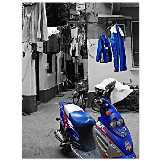 La photo en noir et blanc crée une ambiance nostalgique ou intemporelle, mettant en valeur les formes ,les textures de la moto et des vêtements suspendus.