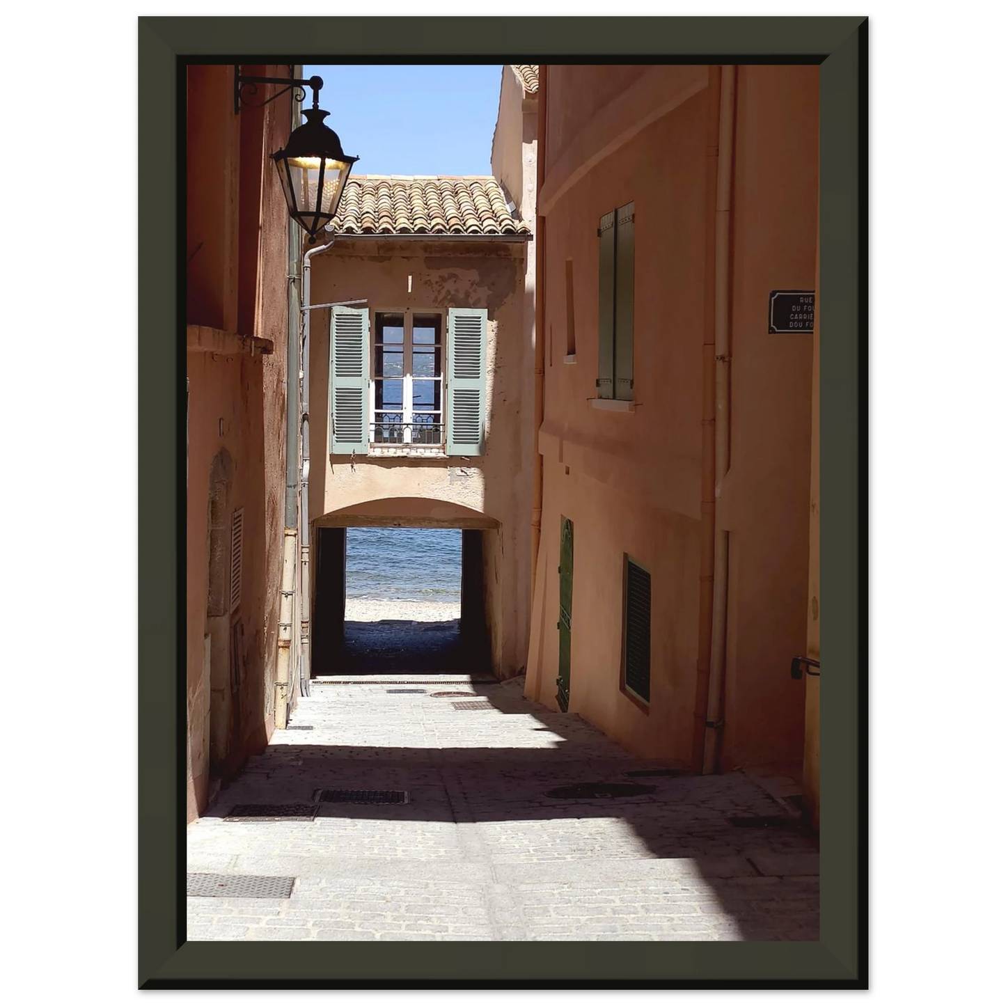 Photo d'art d'une ruelle ombragée à Saint-Tropez menant vers la mer Méditerranée avec architecture provençale