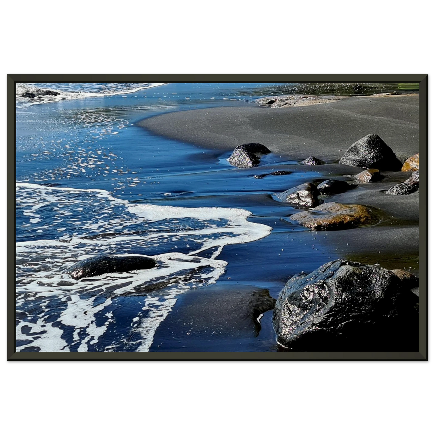 Photographie d'art d'une plage de sable noir volcanique avec écume de mer blanche et rochers humides, format 30x45 cm | Kellestom
