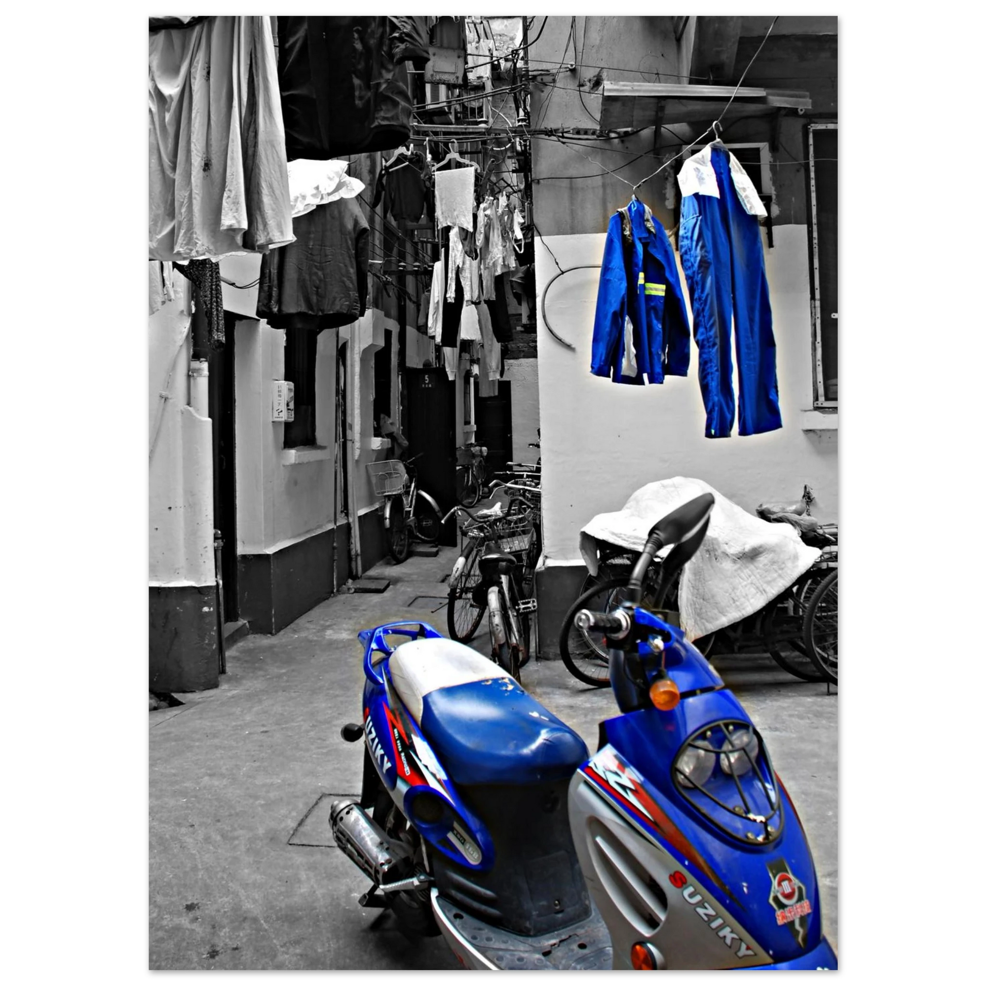 La photo en noir et blanc crée une ambiance nostalgique ou intemporelle, mettant en valeur les formes ,les textures de la moto et des vêtements suspendus.Shanghai moto suziky